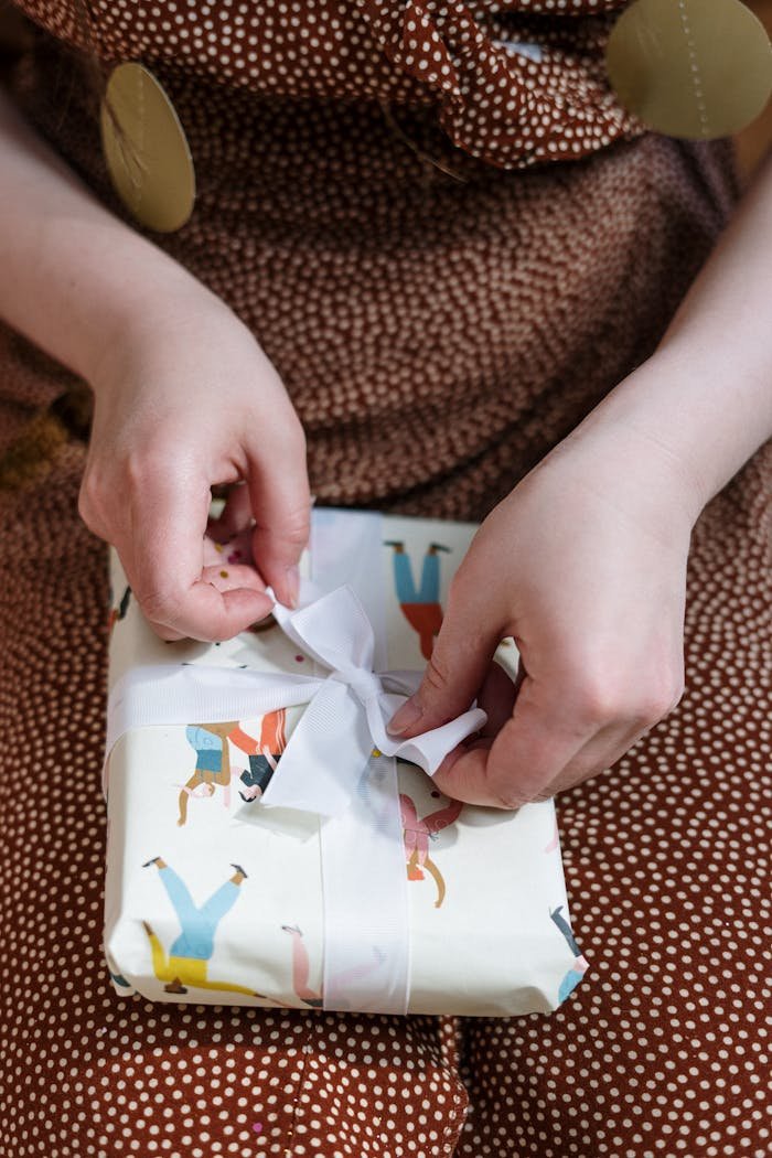 Close-up of a woman unwrapping a gift with playful wrapping paper and ribbon indoors.